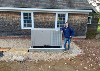 A man stands beside a generator outside a house, ready to provide power during an outage.