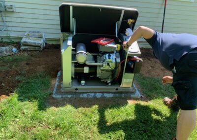 A man diligently working on a small generator in the yard, ensuring a steady power supply.