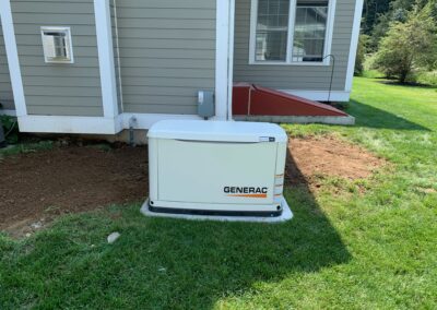 A generator placed on grass beside a house.